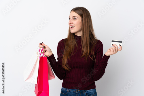 Young woman over isolated white background holding shopping bags and a credit card