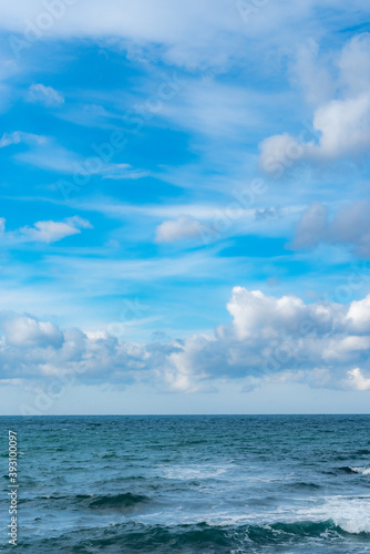 青空に浮かぶ雲とエメラルドグリーンの海の地平線
