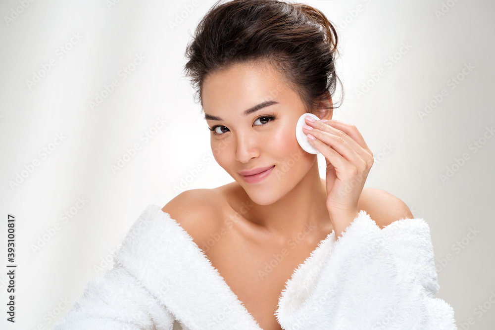 Woman removing makeup, holds cotton pads near face. Photo of asian woman with perfect skin on white background. Beauty and skin care concept Woman removing makeup, holds cotton pads near face. Photo of asian woman with perfect skin on white background. Beauty and skin care concept
