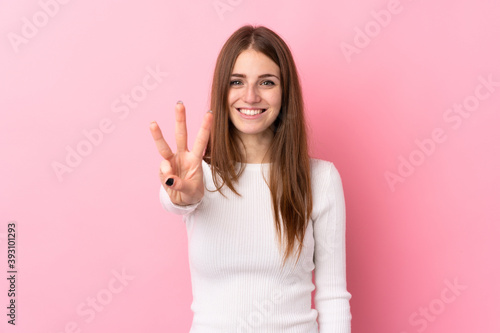 Young woman over isolated pink background happy and counting three with fingers