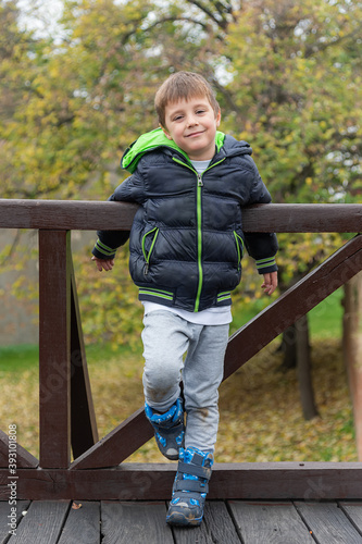 A boy on a wooden bridge. Happy child boy is posing on an autumn day.