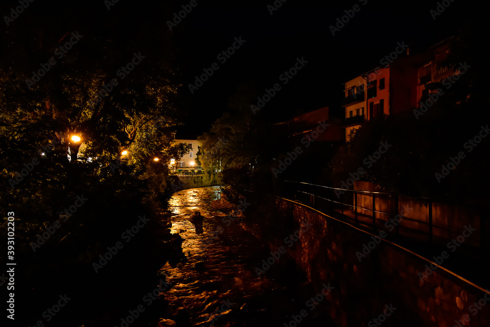 A picturesque view of a small mountain river flowing through a French medieval alpine village at night (Puget-Theniers, Alpes-Maritimes, Provence-Alpes-Cote-d'Azur, France)