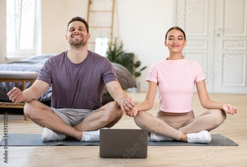 Couple Meditating Together Doing Online Yoga At Laptop At Home