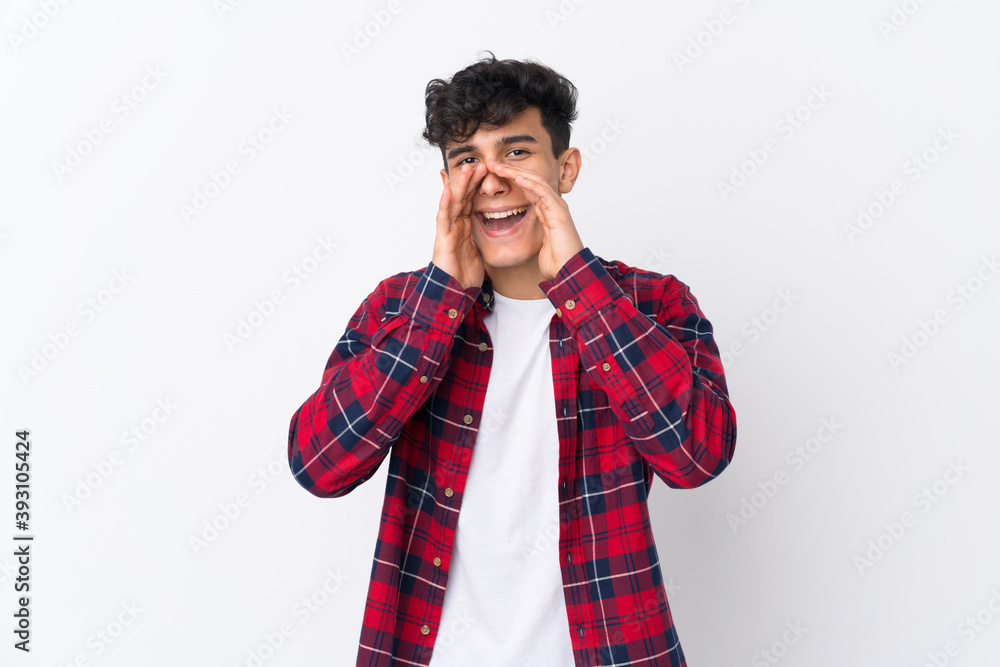 Young Argentinian man over isolated white background shouting and announcing something Young Argentinian man over isolated white background shouting and announcing something