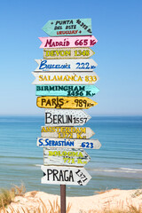 Colorful directions signs on the beach to different cities and countries of the world including Madrid, Paris, Berlin, Praga. Travel destinations concept.