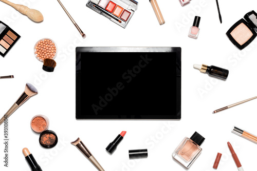Decorative cosmetics and makeup tools on white background with tablet. Online shopping concept. Frame composition with copy space. Flat lay or top view
