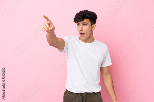 Young Argentinian man over isolated pink background pointing away
