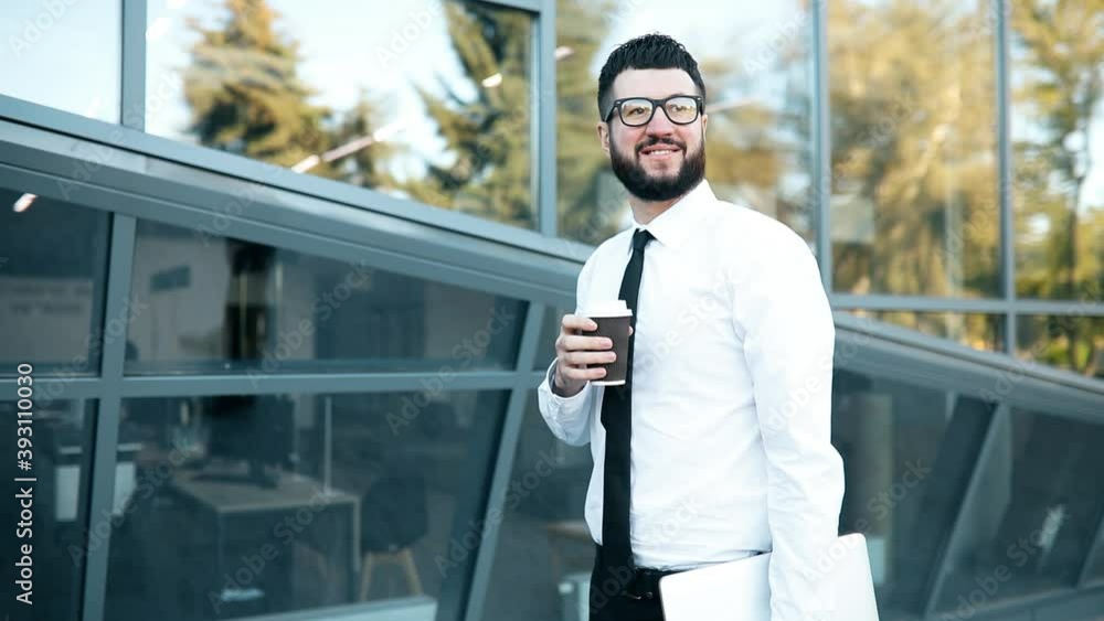 Business man with a beard drinks coffee, walking around the city near the business center, coffee time Business man with a beard drinks coffee, walking around the city near the business center, coffee time