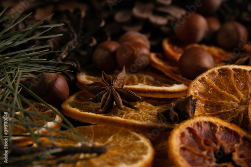 Fototapeta Naklejka Na Ścianę i Meble -  Christmas background with pine tree branches, hazelnuts, anise stars and dried orange on dark board. Christmas decorations. 