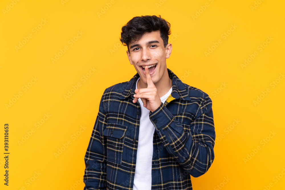 Young Argentinian man over isolated yellow background doing silence gesture Young Argentinian man over isolated yellow background doing silence gesture