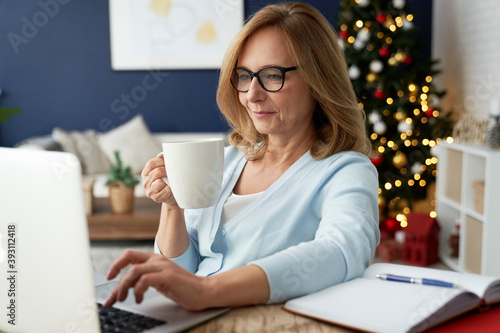 Mature woman drinking coffee in front of laptop