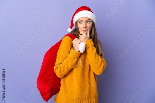 Lithianian woman with christmas hat isolated on purple background having doubts