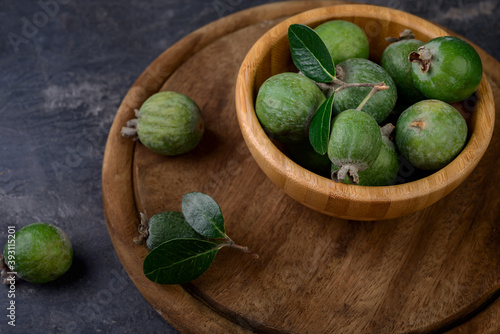 feijoa fruits or pineapple guava, exotic green fruits on wooden bowl in dark background