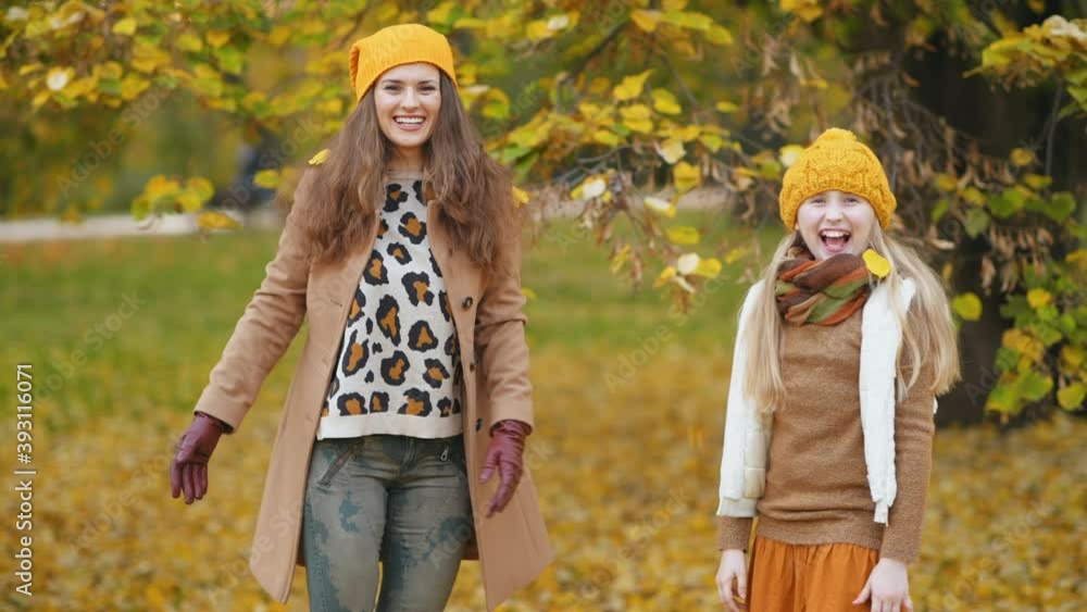 Hello september. happy young mother and child in yellow hats outdoors in the city park in autumn rejoicing. Hello september. happy young mother and child in yellow hats outdoors in the city park in autumn rejoicing.