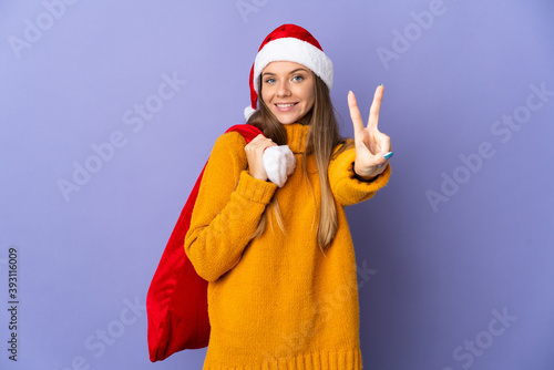 Lithianian woman with christmas hat isolated on purple background smiling and showing victory sign