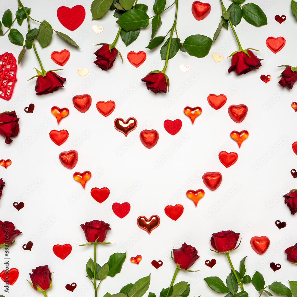Heart symbol made of various red hearts and sweets with fresh red rose flowers on white background. Greeting card, mock up. Love, romance or Valentine's day concept. Flat lay, top view, copy space Heart symbol made of various red hearts and sweets with fresh red rose flowers on white background. Greeting card, mock up. Love, romance or Valentine's day concept. Flat lay, top view, copy space