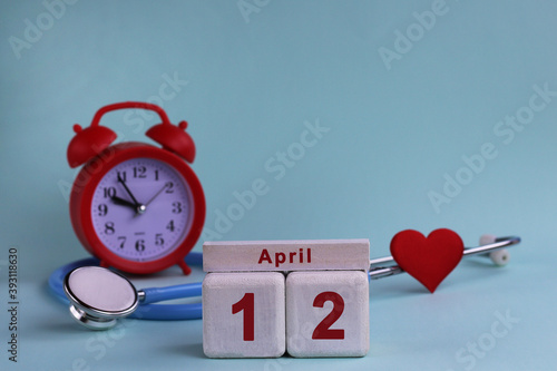 April 12st. White wooden calendar blocks with date, clock and stethoscope on a blue pastel background. Selective focus. health concept photo