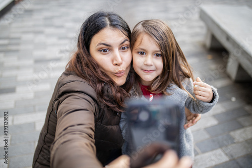 Mother and daughter taking a selfie while making funny faces © Christian