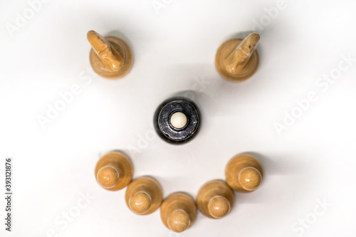 Wooden chess pieces. The black Queen is surrounded by white pawns and two knights looking at the center, focus on the black Queen on top of her head, on a white background. View from the top part to f
