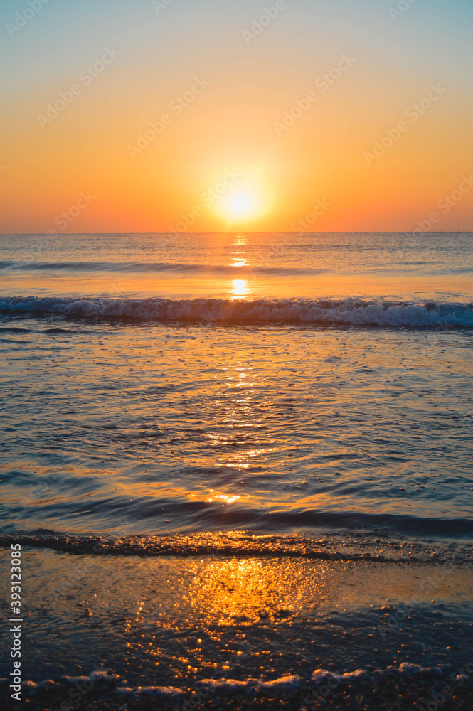 Beautiful summer sunset at the beach, waves and sand