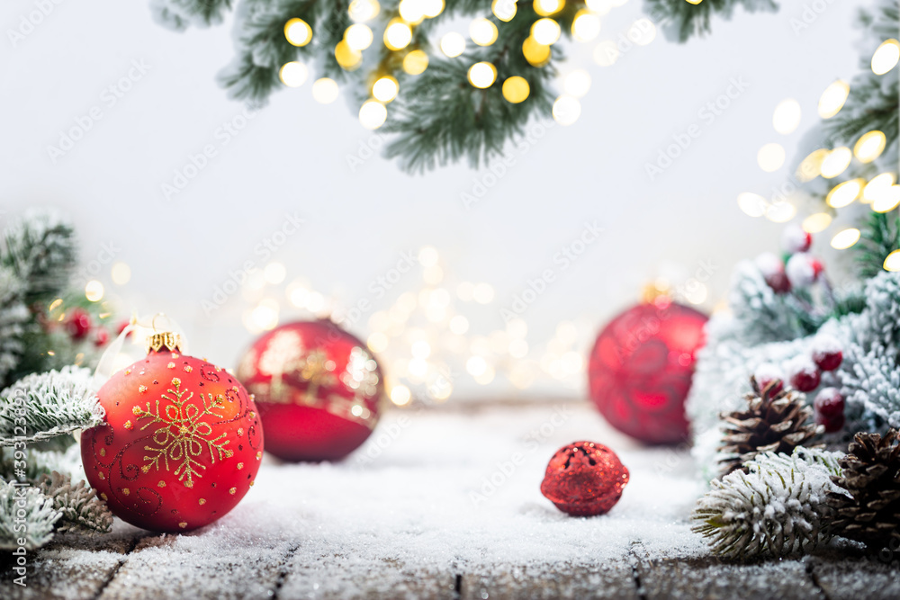 Christmas red decorations on snow with fir tree branches and christmas lights. Winter Decoration Background with copy space for text Christmas red decorations on snow with fir tree branches and christmas lights. Winter Decoration Background with copy space for text