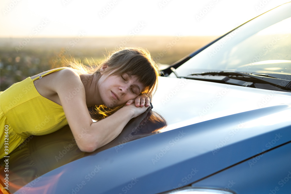 Young woman driver resting near her car in warm summer evening.