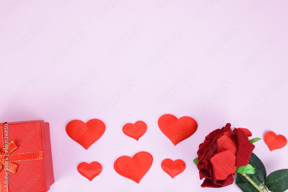 Gift box, artificial red rose bud and decorative hearts on a pink background with a copy space. Valentine's day concept.