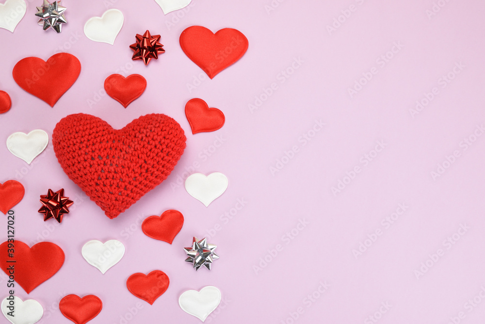 Top view of a bright collage of decorative hearts, foil stars with a large knitted heart between them. Valentine's day concept.