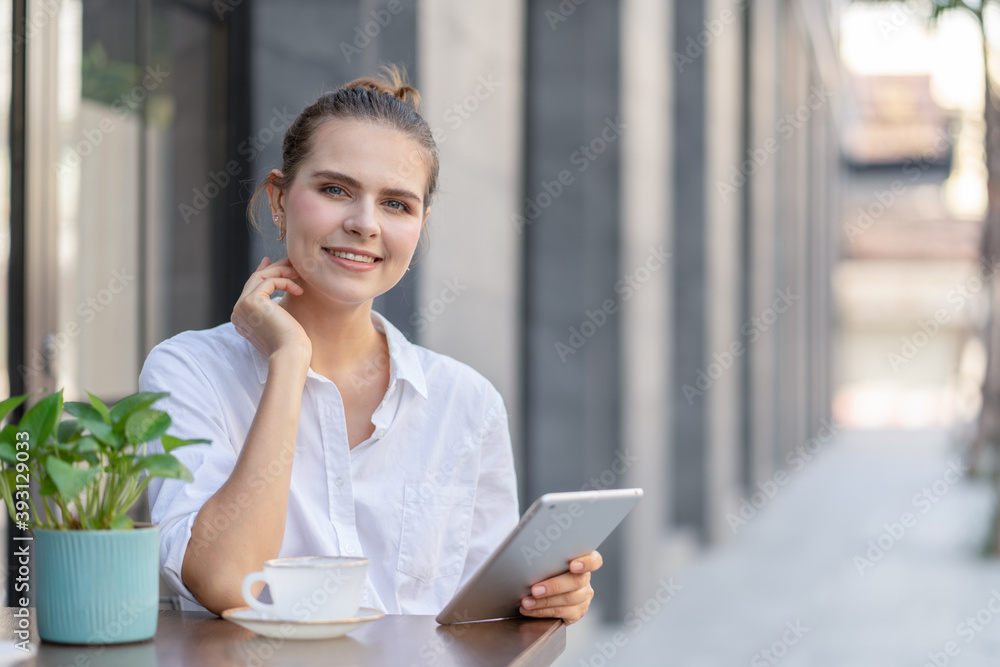 Beautiful young woman sitting hold digital tablet look at camera at street cafe outside Beautiful young woman sitting hold digital tablet look at camera at street cafe outside