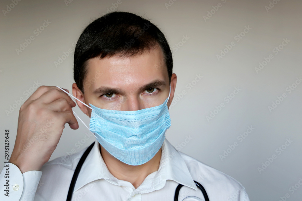 Doctor removing disposable face mask. Concept of coronavirus protection, tired physician after work Doctor removing disposable face mask. Concept of coronavirus protection, tired physician after work