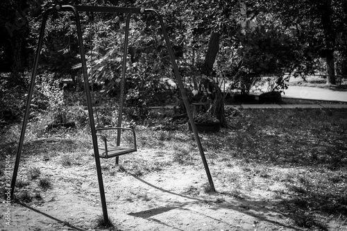 Empty swing in an abandoned playground. Gloomy swing
