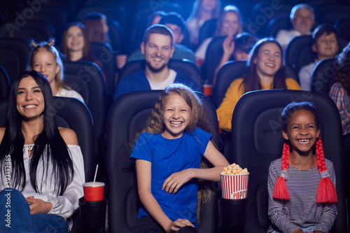 Multiracial audience enjoying cartoon in cinema hall.