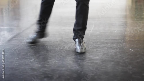 Single male tap dancer wearing black trousers and leather shoes dancing simple irish dance. photo