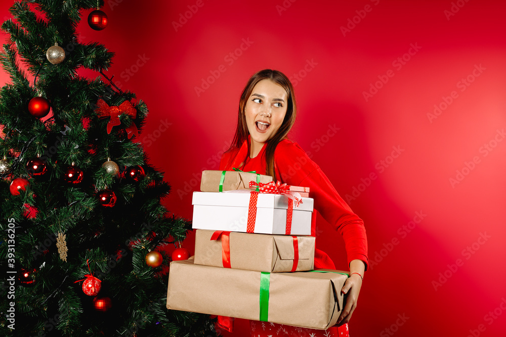 Surprised girl in pajamas holding a stack of gifts at home by the tree. The concept of New Year's gift, winter shopping. Surprised girl in pajamas holding a stack of gifts at home by the tree. The concept of New Year's gift, winter shopping.