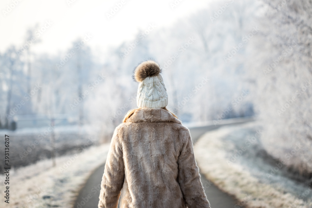 Woman wearing fur coat and knit hat walk outdoors in winter