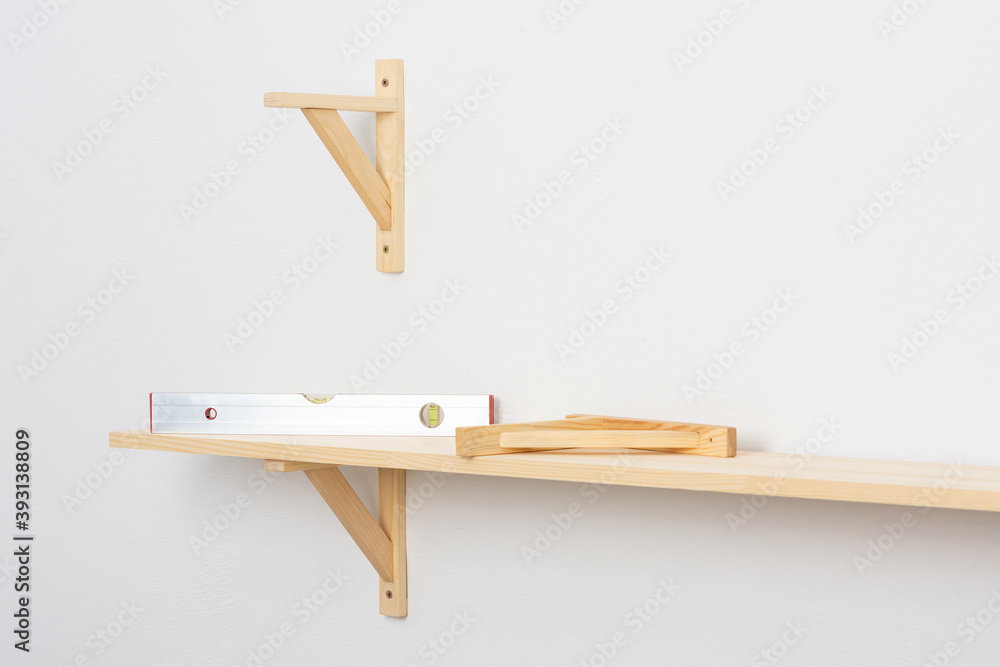 The process of fixing the wooden shelf to the wall, the level tool checks the evenness of the shelf The process of fixing the wooden shelf to the wall, the level tool checks the evenness of the shelf