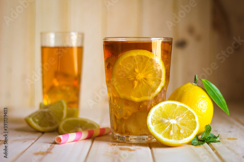 Glasses of ice tea with lemon slices on wooden background