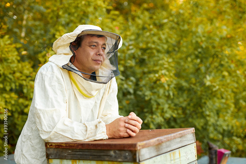 portrait of thoughtful caucasian beekeeper in uniform at work place, he is keen on taking care of beers