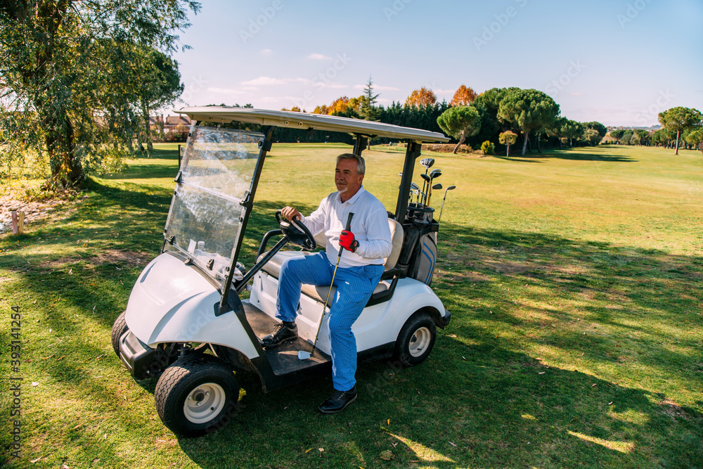 Portrait of senior golfer sitting in his golf buggy in autumn Portrait of senior golfer sitting in his golf buggy in autumn