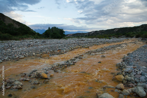 Environmental. View of the yellow river flowing across the rocky valley, mountains and forest at sunset.