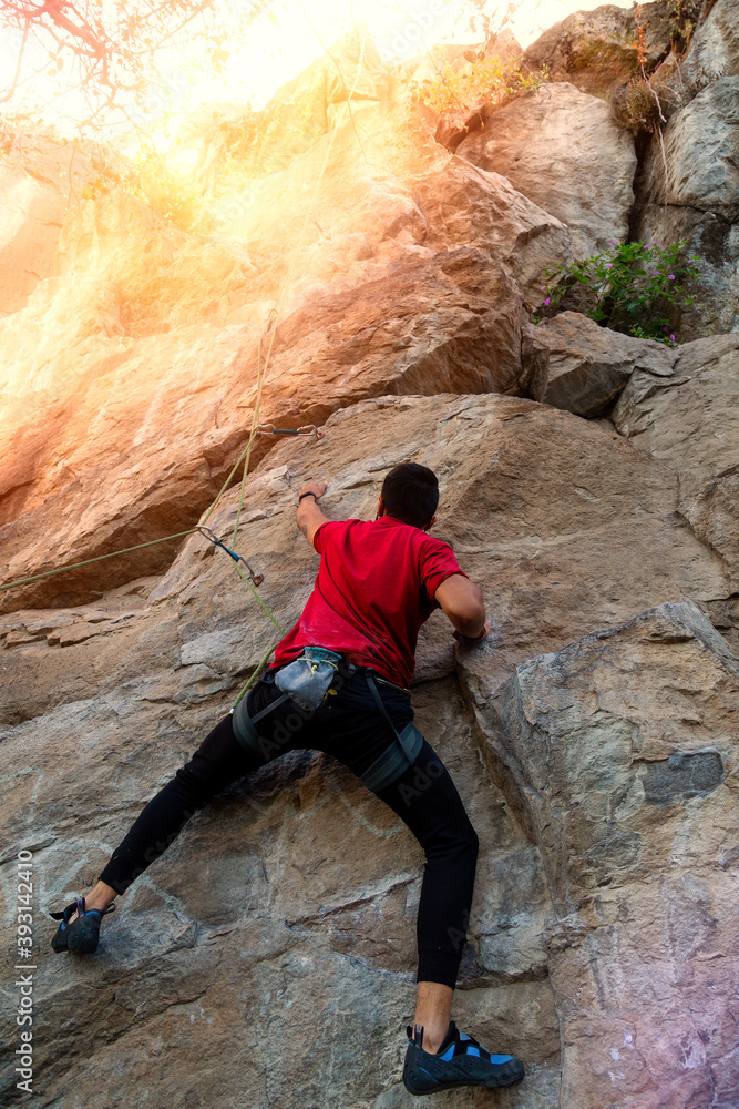 A young man with a rope engaged in the sports of rock climbing on the rock A young man with a rope engaged in the sports of rock climbing on the rock