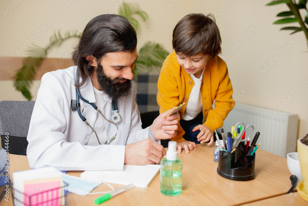 Paediatrician doctor examining a child in comfortabe medical office. Healthcare, childhood, medicine, protection and prevention concept. Little boy trust to doctor and feels calm, positive emotions. Paediatrician doctor examining a child in comfortabe medical office. Healthcare, childhood, medicine, protection and prevention concept. Little boy trust to doctor and feels calm, positive emotions.