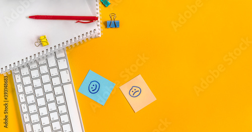 Sad and happy stickers on your desktop next to your keyboard and office supplies. The concept of emotionality of the person at work life concept