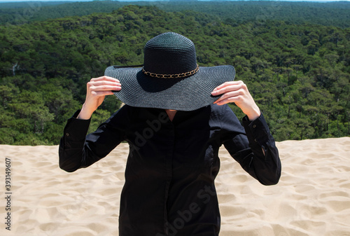 girl on the sand dune holding a black hat... photo