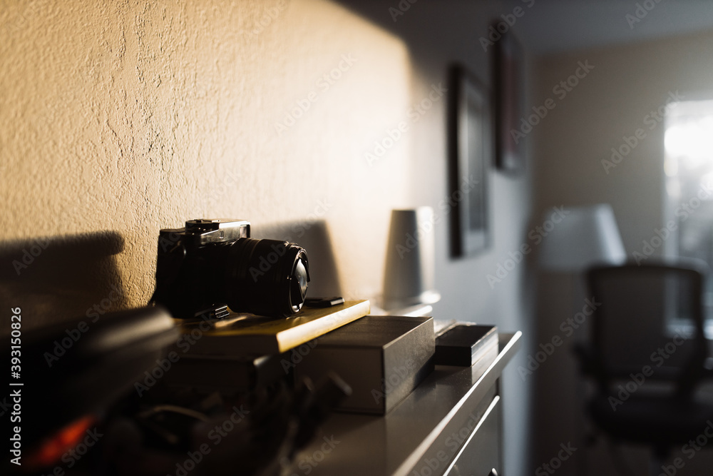 Professional photo camera illuminated by sunlight placed on wooden chest of drawers in room with contemporary interior Professional photo camera illuminated by sunlight placed on wooden chest of drawers in room with contemporary interior