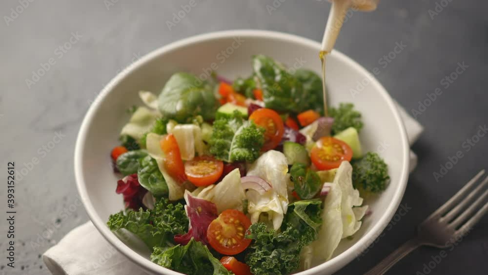 The cook pours a juicy healthy vegetable salad with olive oil, the camera moves to the salad. Cucumbers, tomatoes, lettuce, iceberg lettuce. close-up The cook pours a juicy healthy vegetable salad with olive oil, the camera moves to the salad. Cucumbers, tomatoes, lettuce, iceberg lettuce. close-up