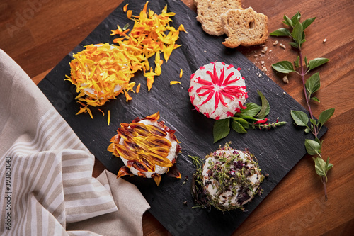 Delicious round shaped curd decorated with edible flower petals and placed on slate board on table in kitchen photo