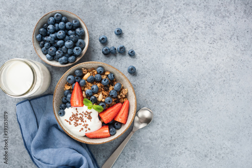 Granola bowl with yogurt and berries in a bowl. Healthy breakfast food. Dieting, fitness food menu concept. Top view copy space