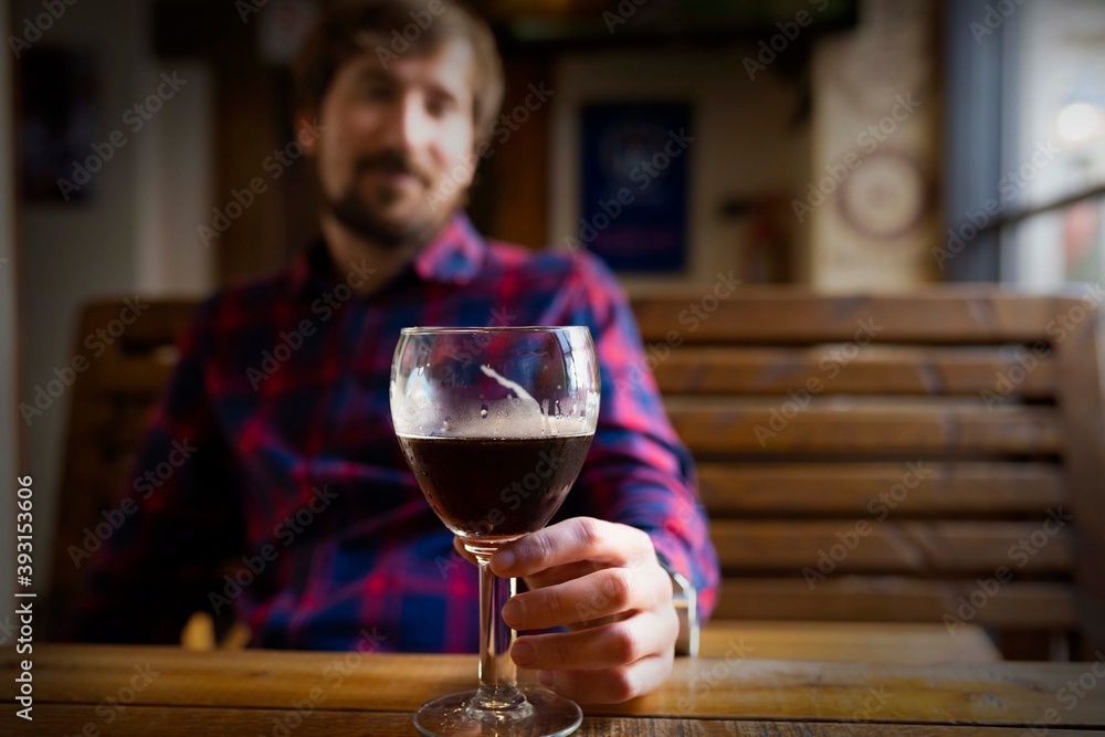 Alcoholism, alcohol addiction concept. A lonely drunk man sits in a bar with alcohol in his hands. Crisis, depression