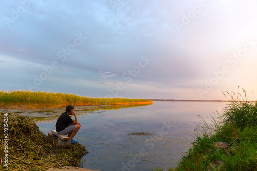 Teenboy sitting and relaxing on lake beach